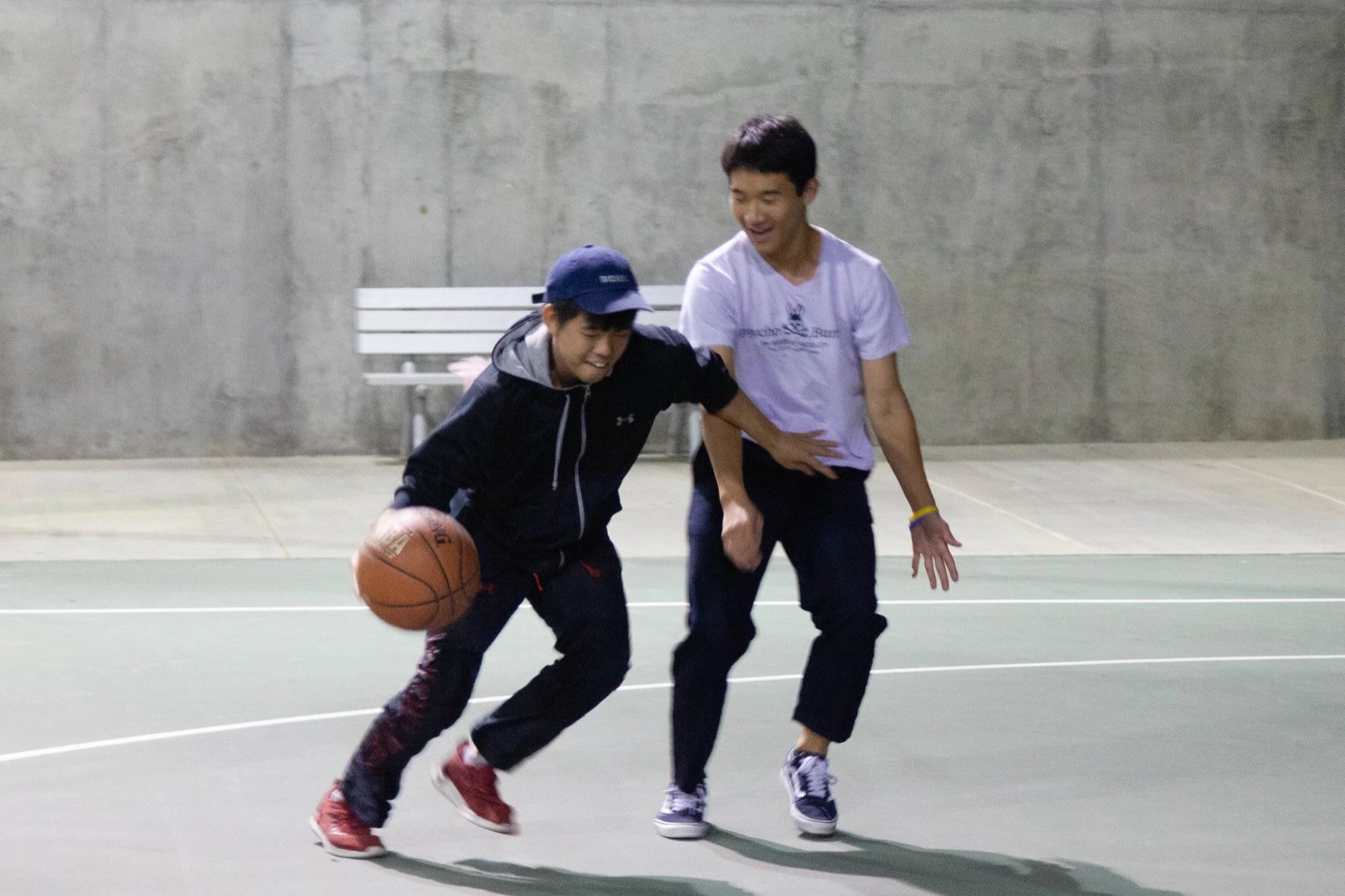 Two people playing one-on-one basketball on an outdoor court