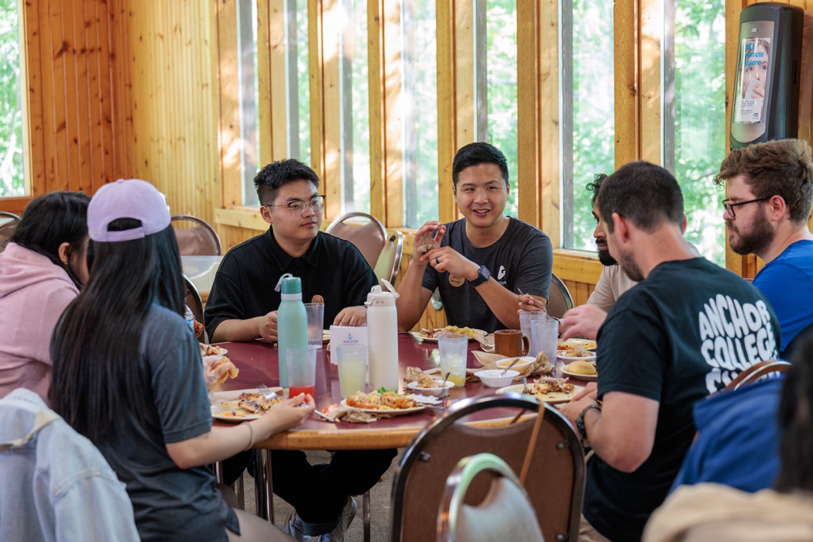 Students and mentors talking over a meal around a long table at an ISMP retreat